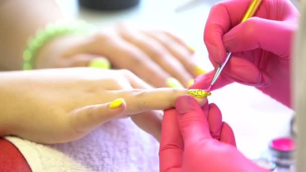 Primer plano de un esteticista aplicando esmalte de uñas a las uñas femeninas en un salón de uñas. Primer plano de una mano de mujer con esmalte de uñas amarillo después de la manicura . — Vídeo de stock