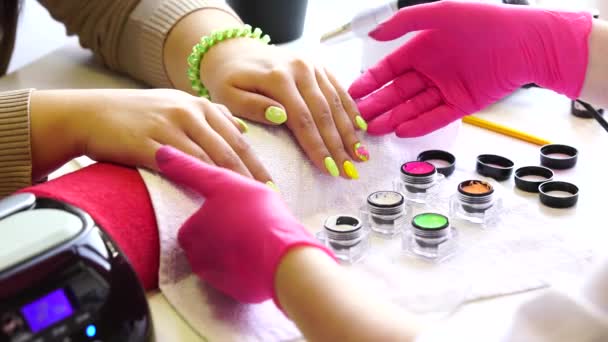 Primer plano de un esteticista aplicando esmalte de uñas a las uñas femeninas en un salón de uñas. Primer plano de una mano de mujer con esmalte de uñas amarillo después de la manicura . — Vídeos de Stock