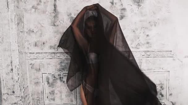 Das Mädchen in weißer Unterwäsche, entfernen Sie dunklen Stoff auf einer hellen Hintergrundwand — Stockvideo