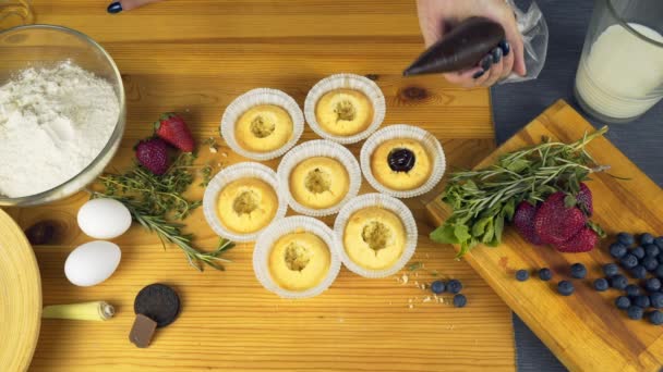 Mujer con negocio de panadería casera piping cream en cupcakes — Vídeos de Stock