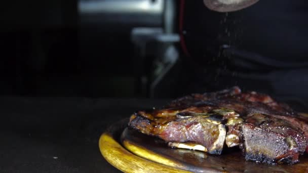 Smažený steak na grilu leží na dřevěném prkénku s zeleninou — Stock video