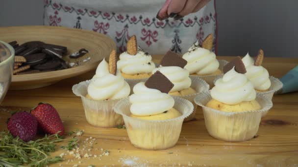 Muffin con crema y chispas de chocolate encima de él se sienta en una mesa de madera brillante — Vídeos de Stock