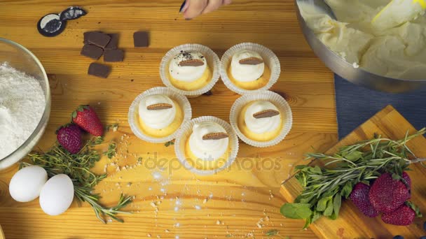 Muffin with cream and chocolate chips on top of him sits on a bright wooden table — Stock Video