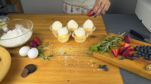 Mãos femininas decorando muffins de chocolate com morango — Vídeo de Stock