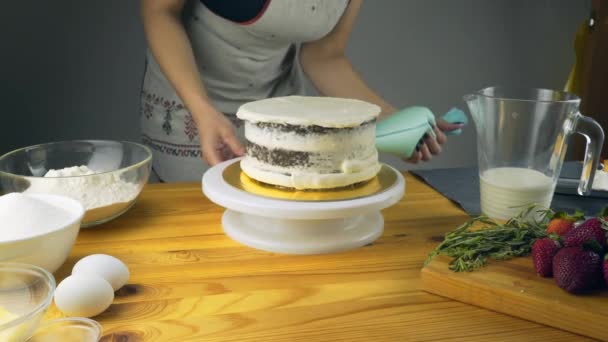 Cukiernik zdobi ciasto i przykryj ją z masłem śmietankowym. Wyroby cukiernicze narzędzia: Łopatka do wyrównania śmietany. Biszkopt czekoladowy z masłem śmietankowym. — Wideo stockowe