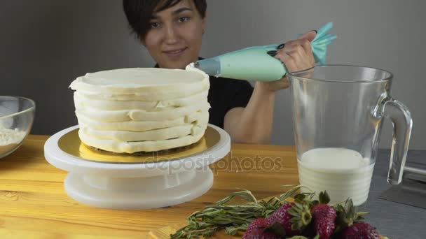 El confitero decora el pastel y lo cubre con crema de mantequilla. Herramientas de confitería: espátula para crema de alineación. Pastel de esponja de chocolate con crema de mantequilla . — Vídeo de stock