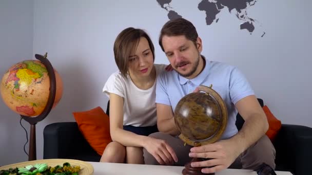 Jovem casal olhar o mapa do mundo para decidir a próxima viagem — Vídeo de Stock
