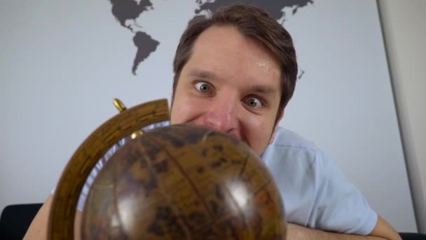 Man looking at globe and picking travel destination at home on the couch — Stock Video