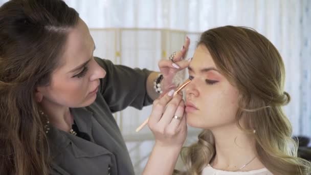 De master in een make-up bereidt model voor weergave in de schoonheidssalon. De make-up artiest doet professioneel een make-up. — Stockvideo