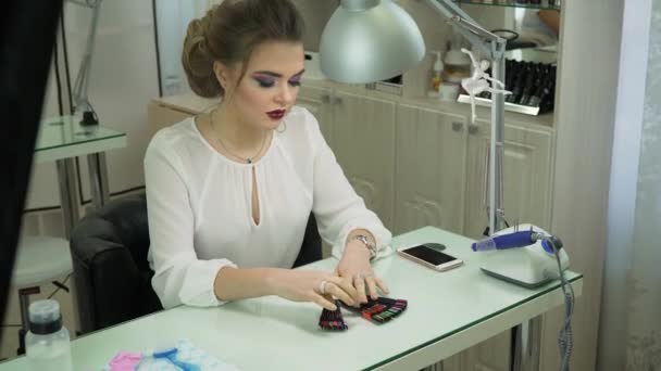 Meisjes ziet een grote collectie van valse nagels, en kiest de juiste kleur en het ontwerp. Ondiepe scherptediepte — Stockvideo