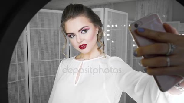 Mulher jovem e bonita tirando foto selfie com telefone celular na frente da lâmpada do anel, tiro estúdio — Vídeo de Stock