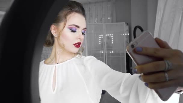 Plan studio de jeune et belle femme prenant des photos selfie avec téléphone portable devant la lampe annulaire — Video