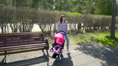 Genç anne dansları bir bebek arabası açık bir sonbahar Park yakınındaki