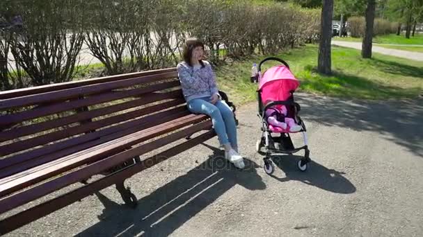Женщина с детской коляской и телефоном в руках — стоковое видео