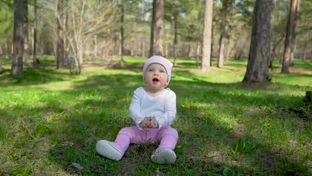 Κοριτσάκι στο πάρκο άνοιξη ή καλοκαίρι κάθεται στο γρασίδι στην ημέρα ηλιοφάνειας — Αρχείο Βίντεο