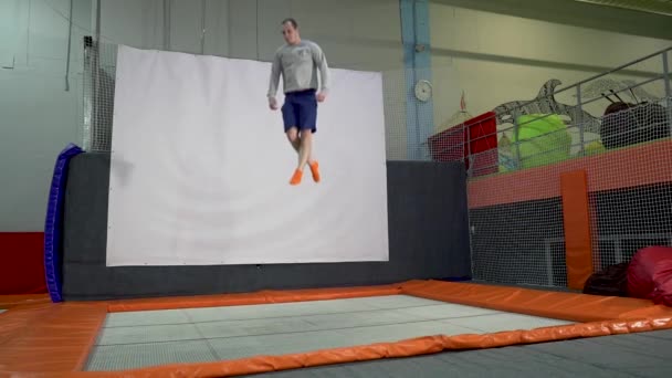 Jonge mannen springen op de Trampoline In binnen speeltuin. Actieve mensen man plezier op sportcentrum. Slow Motion — Stockvideo