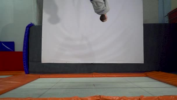 Jóvenes saltando en el trampolín en el patio interior. Gente activa Hombre divirtiéndose en el centro deportivo. Moción lenta — Vídeos de Stock