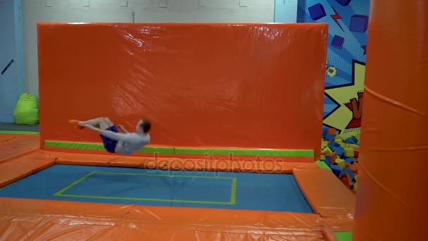 Молодые люди прыгают на батуте в помещении детской площадки. Активные люди Мужчины веселятся в спортивном центре. Slow Motion — стоковое видео