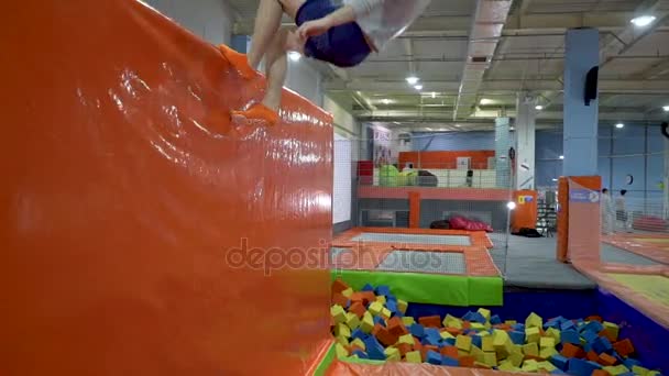 Unge mænd hopper på trampolin i indendørs legeplads. Aktive mennesker mandlige have det sjovt på Sport Center. Langsom bevægelse – Stock-video