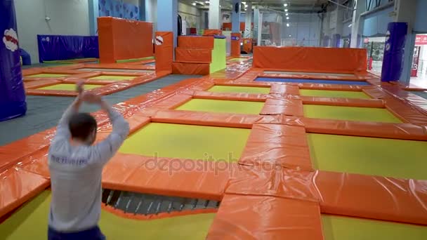 Unga män hoppar på studsmatta i inomhus lekplats. Aktiva människor hane att ha kul på Sport Center. Slow Motion — Stockvideo