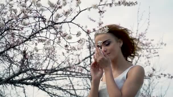 Porträtt av en vacker flicka som luktar rosa blommor i trädgården — Stockvideo