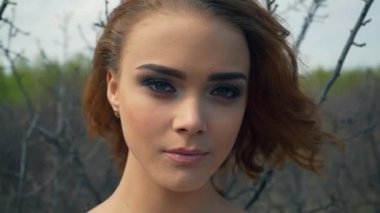 Kızıl saçlı kız parkta portresi. kameraya bak. Beyaz çiçekler