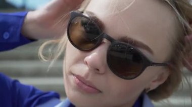 güneş ışığı tarafından beyaz bir elbise ve havacı güneş gözlüğü aydınlatmalı güzellikte genç sarışın kadın