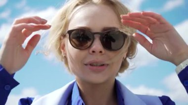 güneş ışığı tarafından beyaz bir elbise ve havacı güneş gözlüğü aydınlatmalı güzellikte genç sarışın kadın