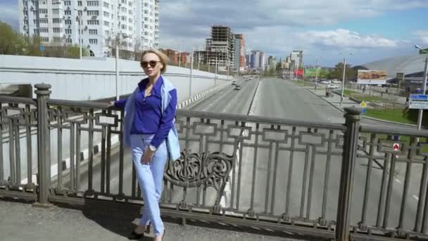 Belle femme d'affaires en costume d'affaires avec des lunettes et une coupe de cheveux courte, se tient sur le pont. Circulation des voitures . — Video