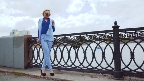 Schöne Geschäftsfrau in einem blauen Hemd, in der Nähe der Flüsse. zu einer Besprechung gehen und glücklich lächeln — Stockvideo