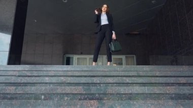 Gülümseyen, çekici iş adamı merdivenlerden üst kısmında duruyor