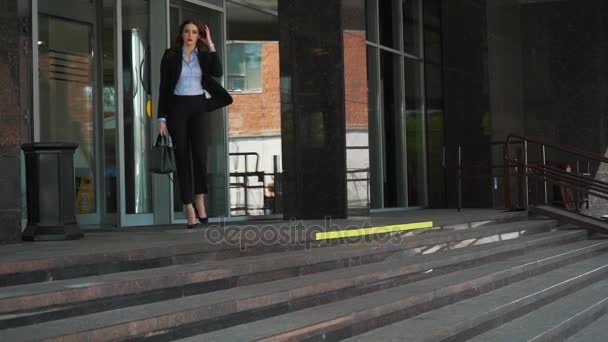 Mujer de negocios inteligente de la ciudad caminando cerca del enorme centro de negocios — Vídeo de stock