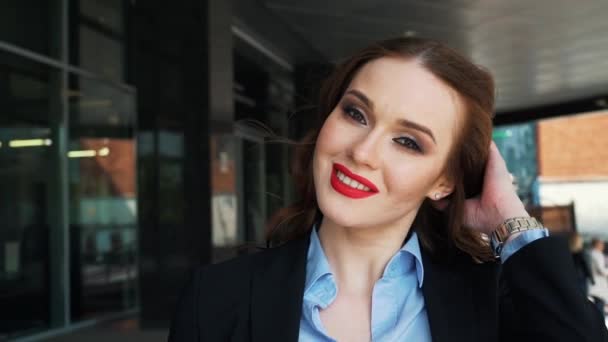 Sexy verleidelijke vrouw met rode lippenstift en staande op de trap in de hal van het kantoorgebouw en kijken naar de camera — Stockvideo