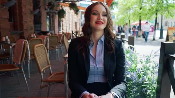 Бизнесмен, сидящая в кафе и разговаривающая с камерой, устойчивая камера снимает — стоковое видео
