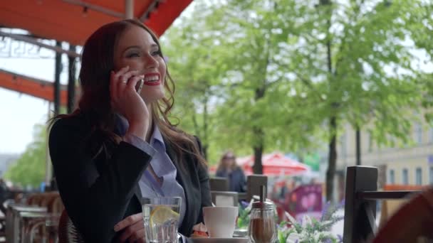 Aantrekkelijke zakenvrouw dragen pak met behulp van Smartphone in een outdoor Cafe, koffie drinken. Slow-Motion. Professional Business Woman praten communiceren over het buitenleven cellphone. Business stadsleven — Stockvideo