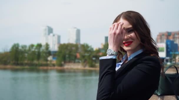 Porträtt av en lycklig ung affärskvinna som står med vikta hand mot urbana staden bakgrund — Stockvideo