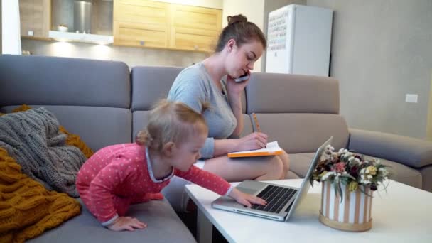 Mulher mãe trabalhando com um bebê em casa atrás de um computador através da Internet — Vídeo de Stock