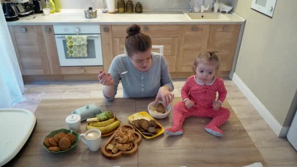 Rodzina, jedzenie, dziecko, odżywianie i koncepcję ojcostwa - szczęśliwa matka młody jedzą śniadanie z dziecko siedzi na stole w domu, jedzenie sera — Wideo stockowe