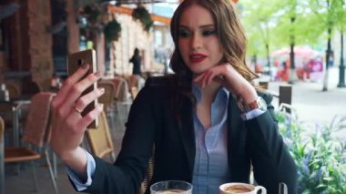 İş kıyafeti içindeki lüks bir genç kız kendini bir kafede selfie yapar.