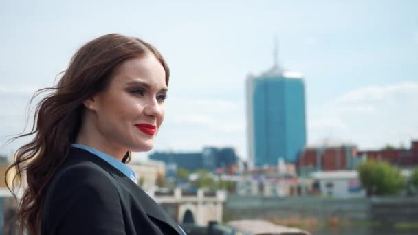 Retrato de una joven mujer de negocios feliz de pie con la mano doblada contra el fondo urbano de la ciudad — Vídeos de Stock