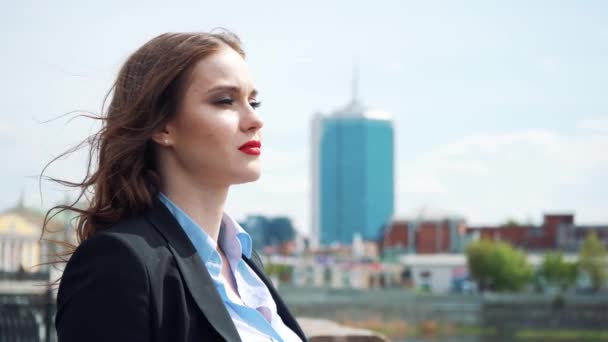 Retrato de una joven mujer de negocios feliz de pie con la mano doblada contra el fondo urbano de la ciudad — Vídeos de Stock