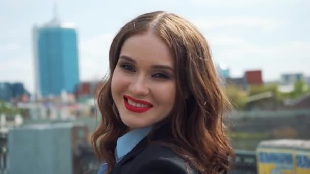 Porträtt av en lycklig ung affärskvinna som står med vikta hand mot urbana staden bakgrund — Stockvideo