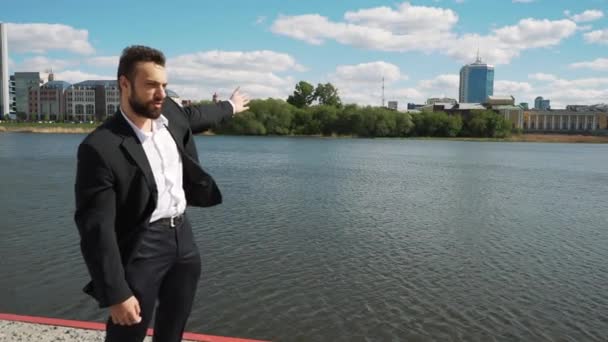 Jovem bonito homem com barba cheia hipster fala com câmera cidade em segundo plano — Vídeo de Stock