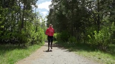 Erken sabah güzel kız pembe kazaklı bir arka plan, ağaçlar ile genç yapraklar üzerinde erken ilkbaharda ormanda koşu, aktif bir yaşam tarzı yol açar