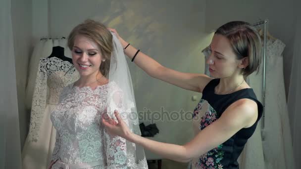 Braut im Kleidergeschäft für Hochzeitskleider wählt sie ein Kleid und der Designer unterstützt sie — Stockvideo