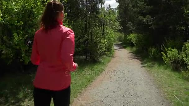 Fitness träning utomhus. Sport kvinna kör genom skogen. Shes i gott humör och en stor figur. Lövskog efter regnet. — Stockvideo