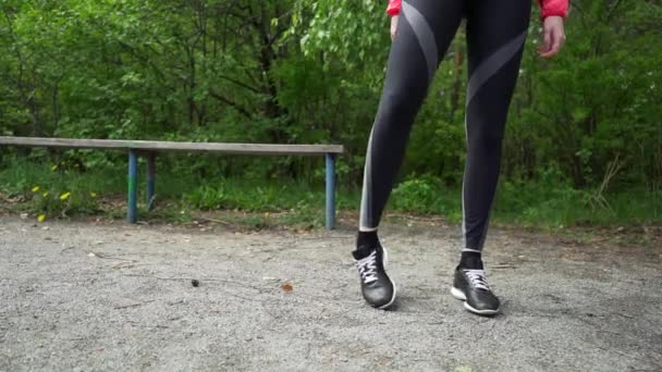 Νεαρός γυμναστήριο γυναίκα δρομέας τεντώνοντας τα πόδια πριν από την εκτέλεση — Αρχείο Βίντεο