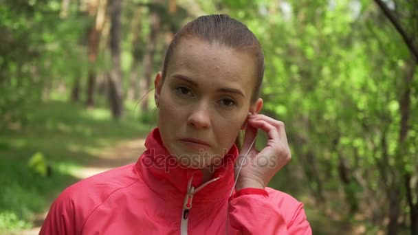 Joven hermosa mujer corriendo en el parque de otoño y escuchando música con auriculares . — Vídeos de Stock