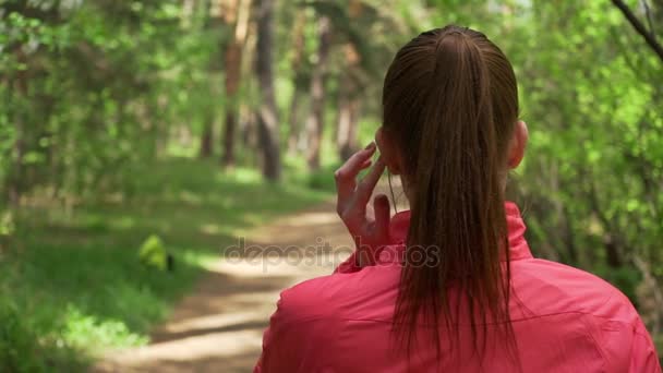 Giovane bella donna che corre nel parco autunnale e ascolta musica con le cuffie . — Video Stock