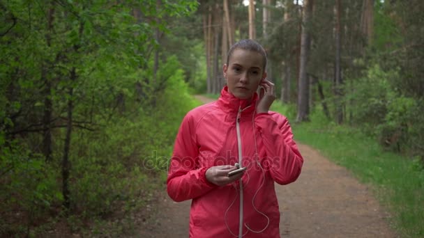 Молодая красивая женщина бегает в осеннем парке и слушает музыку в наушниках . — стоковое видео